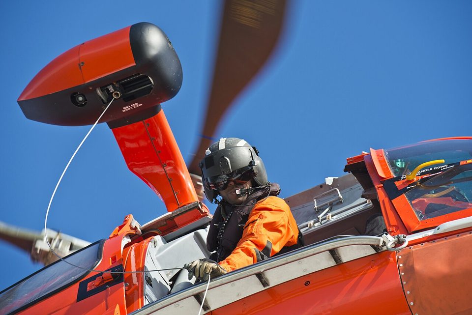 Ein Rettungsschwimmer wird von einem Hubschrauber an der Winde zu einem Boot abgelassen.